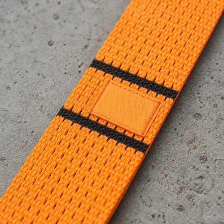 Close-up of an endless web sling band showing the black transverse working load limit stripes and the blank sewn label patch